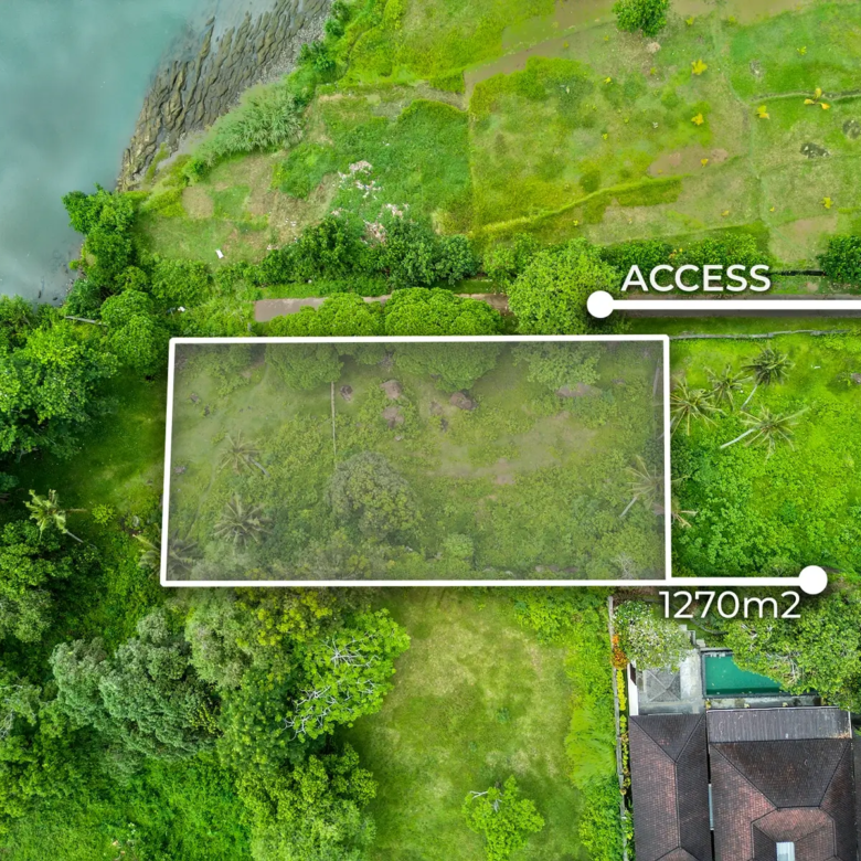 Drone views of 1,270m2 riverside land for sale in Pulukan Bali featuring lush tropical surroundings, river access, ocean views, and nearby villas.