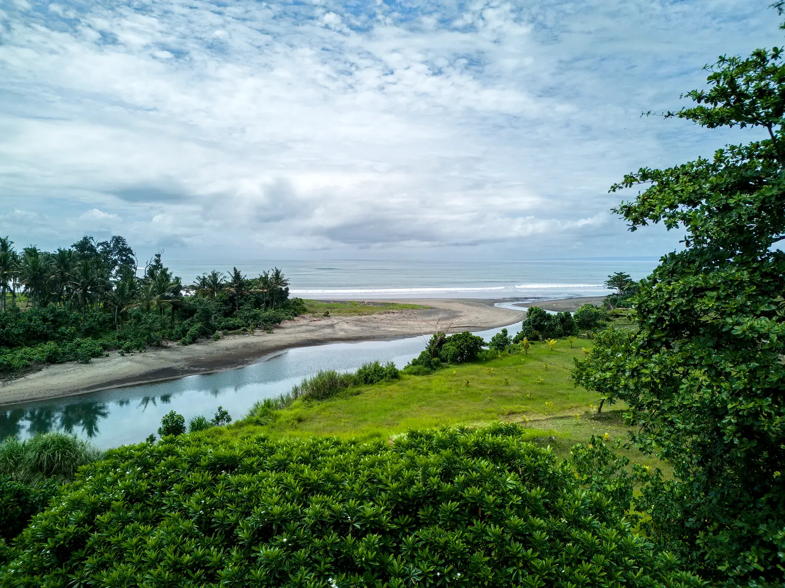 Scenic river and ocean view from Pulukan Bali land overlooking greenery and natural landscape.