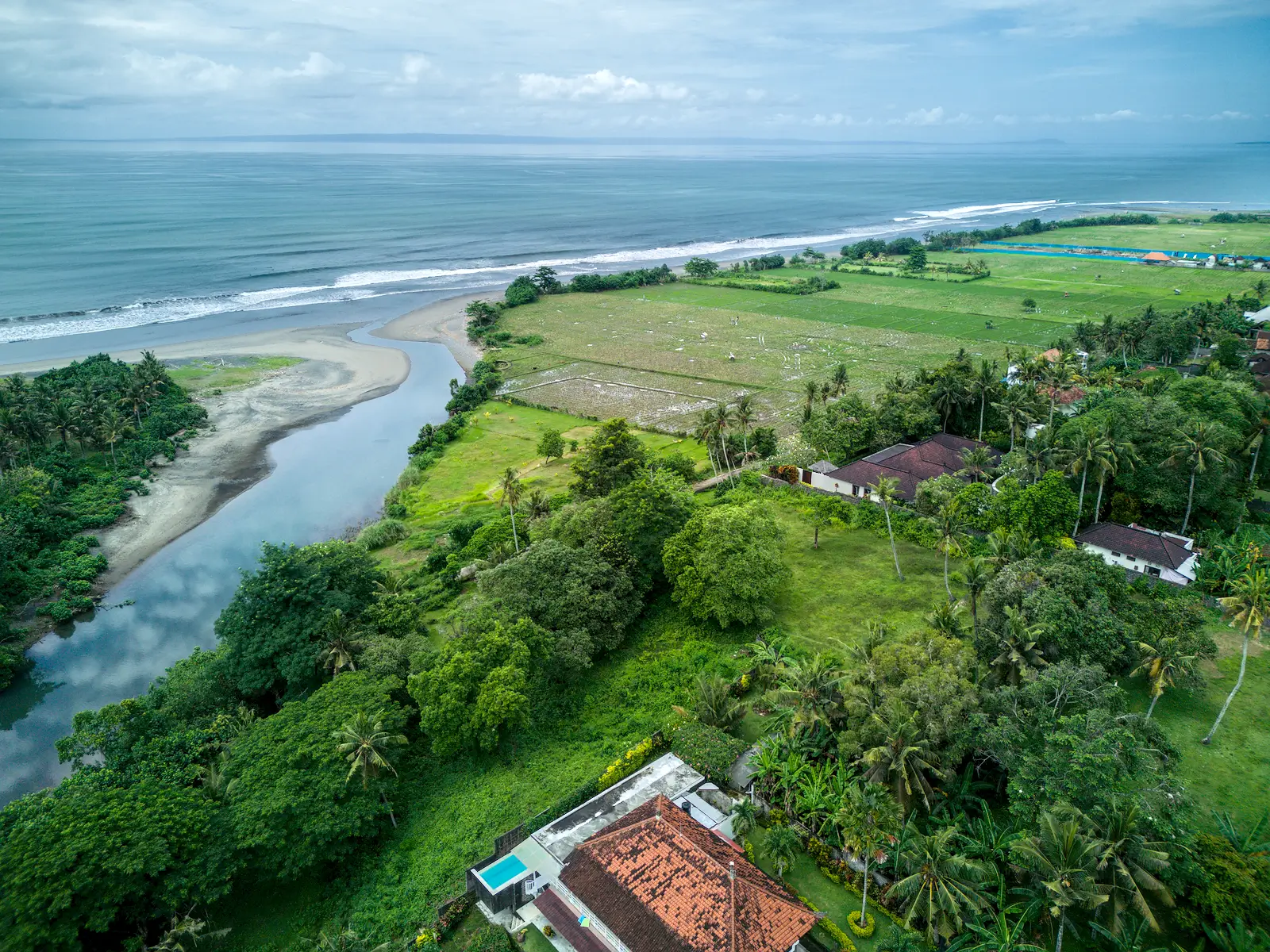 High-angle ocean and river panorama showing Pulukan greenbelt land and neighboring villas.