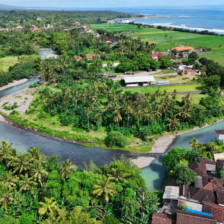 Drone panorama of Medewi river bend and green landscape leading to ocean surf breaks in West Bali