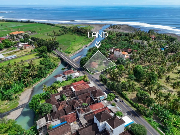 Aerial view of 1,530m2 land for sale in Medewi Bali near the river, bridge, and surf beach with lush tropical surroundings
