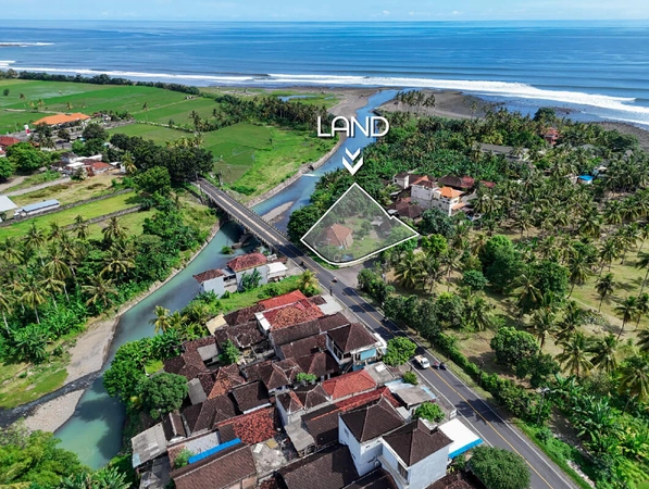 Aerial view of 1,530m2 land for sale in Medewi Bali near the river, bridge, and surf beach with lush tropical surroundings