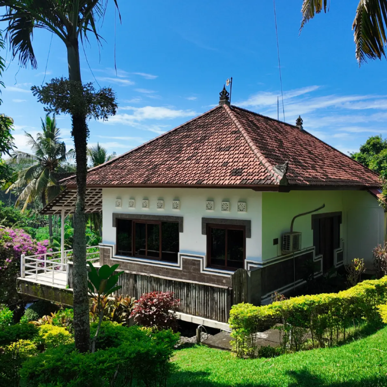 Front view of Balinese villa with red-tiled roof and lush landscaped garden in Pulukan