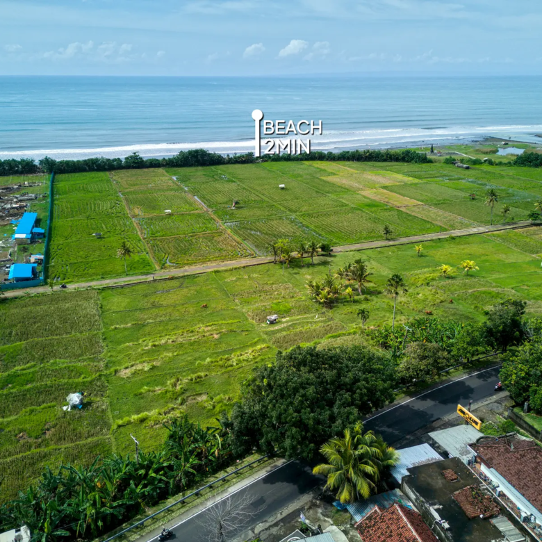 Wide aerial photo of West Bali land for sale only 2 minutes from the beach, surrounded by green rice fields and close to ongoing development projects.