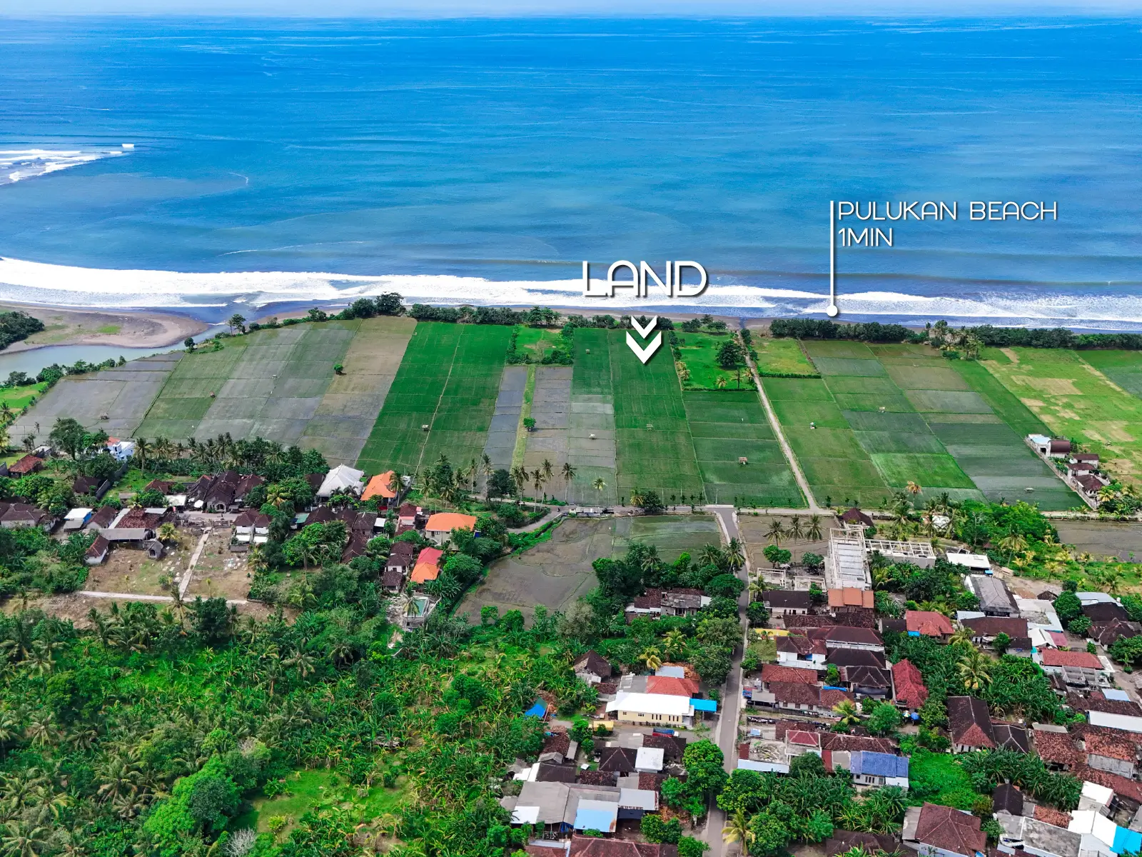 Aerial photo of Pulukan land for sale just 1 minute from the beach, featuring expansive rice fields, ocean waves, and nearby residential village.