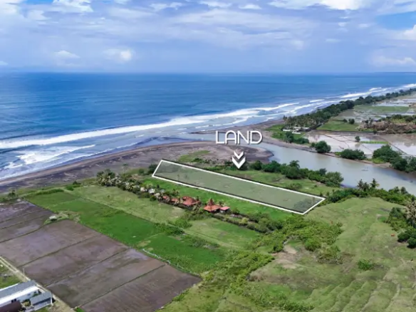 Aerial view of beachfront land for sale in West Bali, outlined along the coastline with ocean waves and river estuary in the background