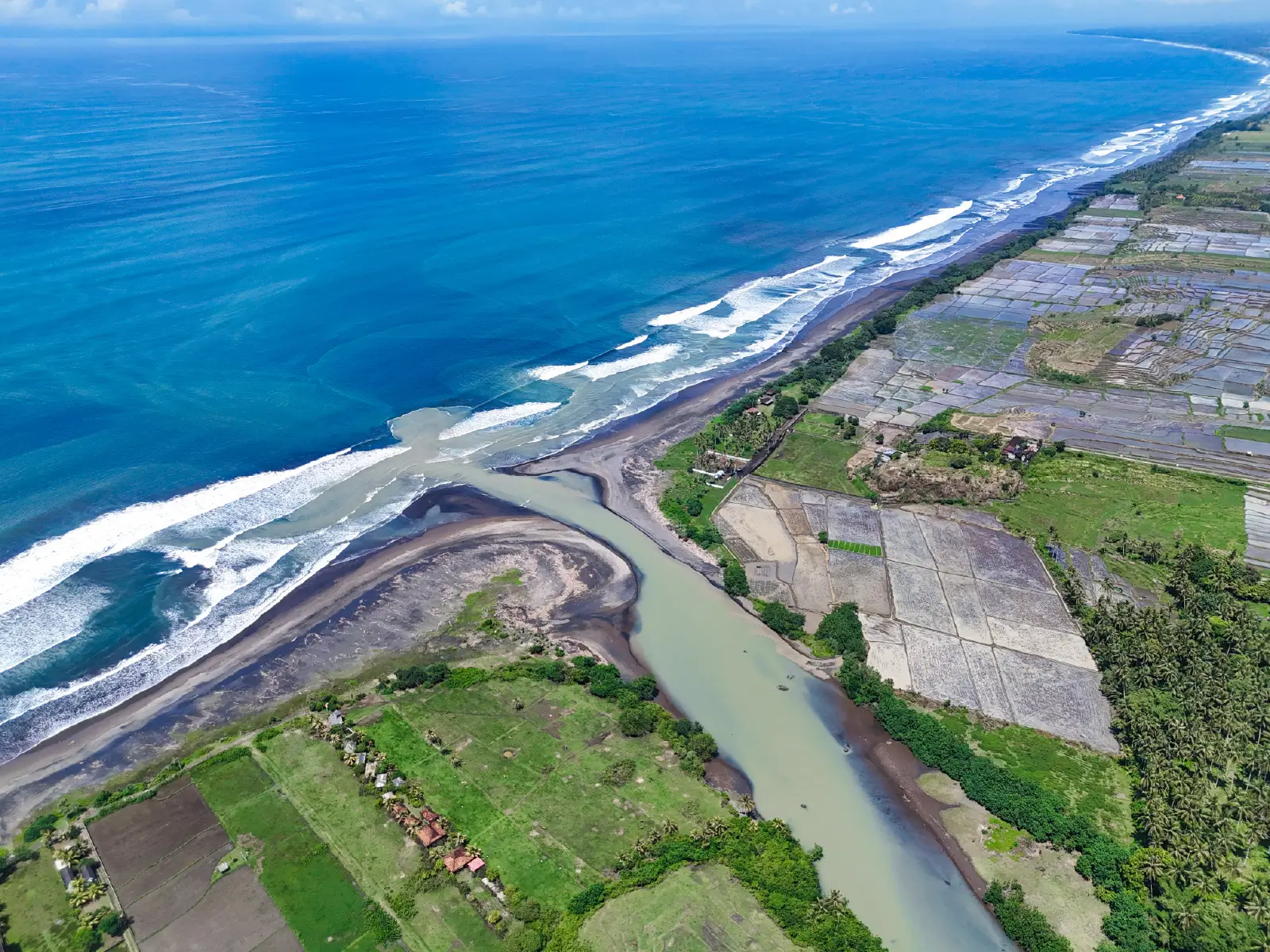 yehsumbul 3-00008 Wide aerial coastal landscape of West Bali featuring ocean waves, river estuary, and expansive rice fields stretching along the shoreline