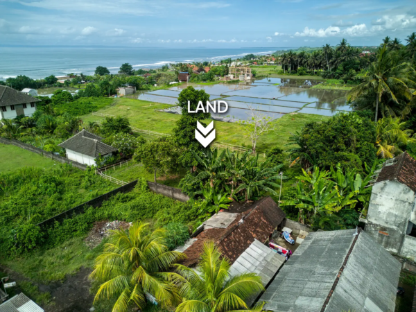 yehsumbul 6-00002 Aerial view of a 620 m² land plot for sale in West Bali, surrounded by village homes, tropical greenery, and rice fields with ocean views