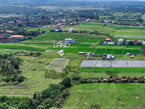 Aerial view of a land plot for sale in West Bali, surrounded by green rice fields and village homes in a peaceful coastal area