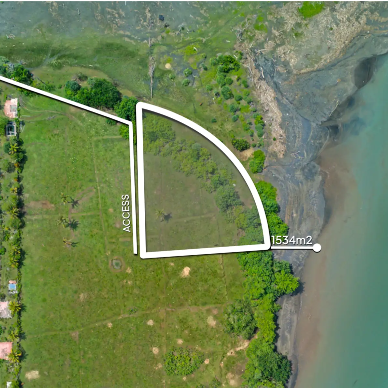 Top-down drone image of a 1,534 m² riverfront land plot in West Bali, showing curved beachfront boundary, private access road, and turquoise river frontage.