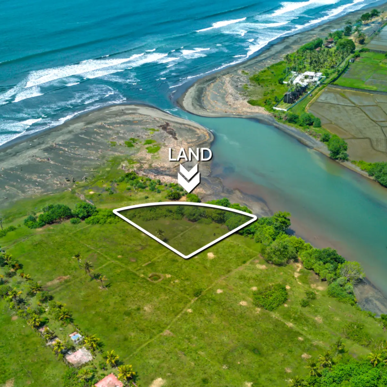 Top-down drone image of a 1,534 m² riverfront land plot in West Bali, showing curved beachfront boundary, private access road, and turquoise river frontage.