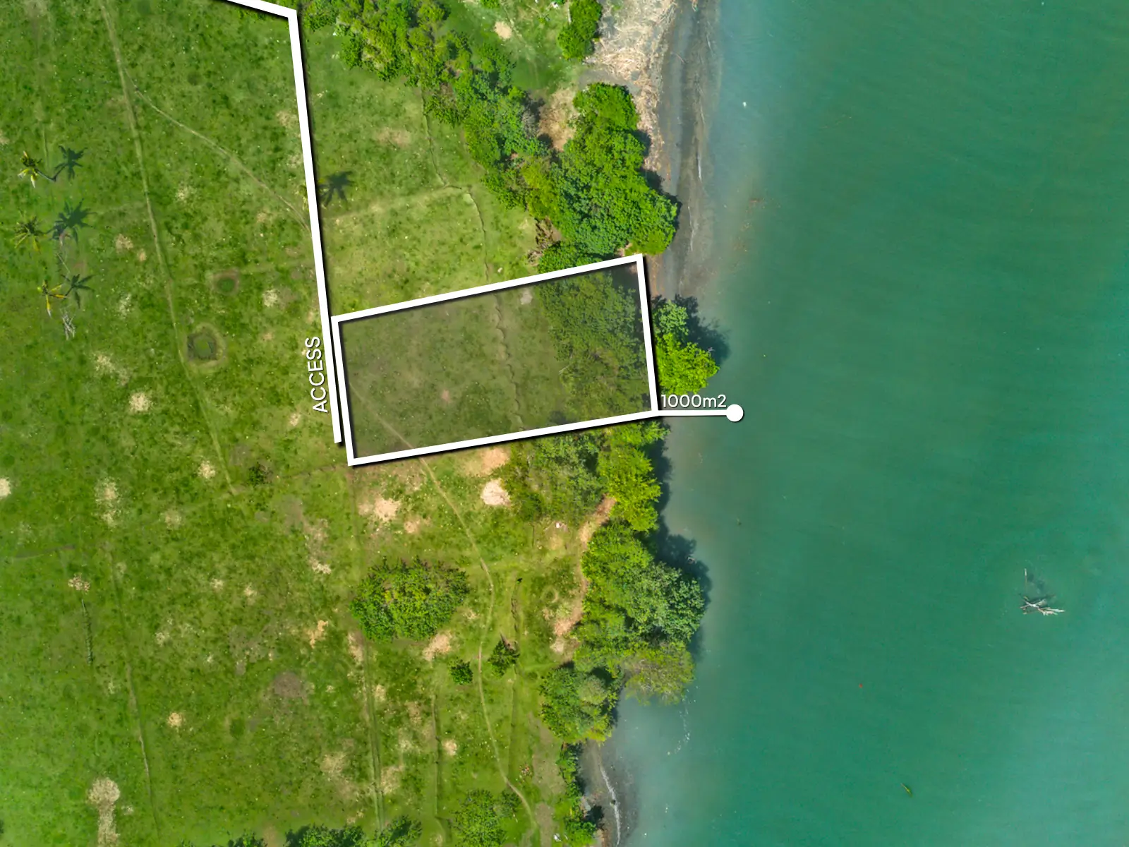Top-down drone image of a 1,000 m² riverfront land plot in West Bali, showing curved lagoon boundary, private access road, and lush green surroundings.