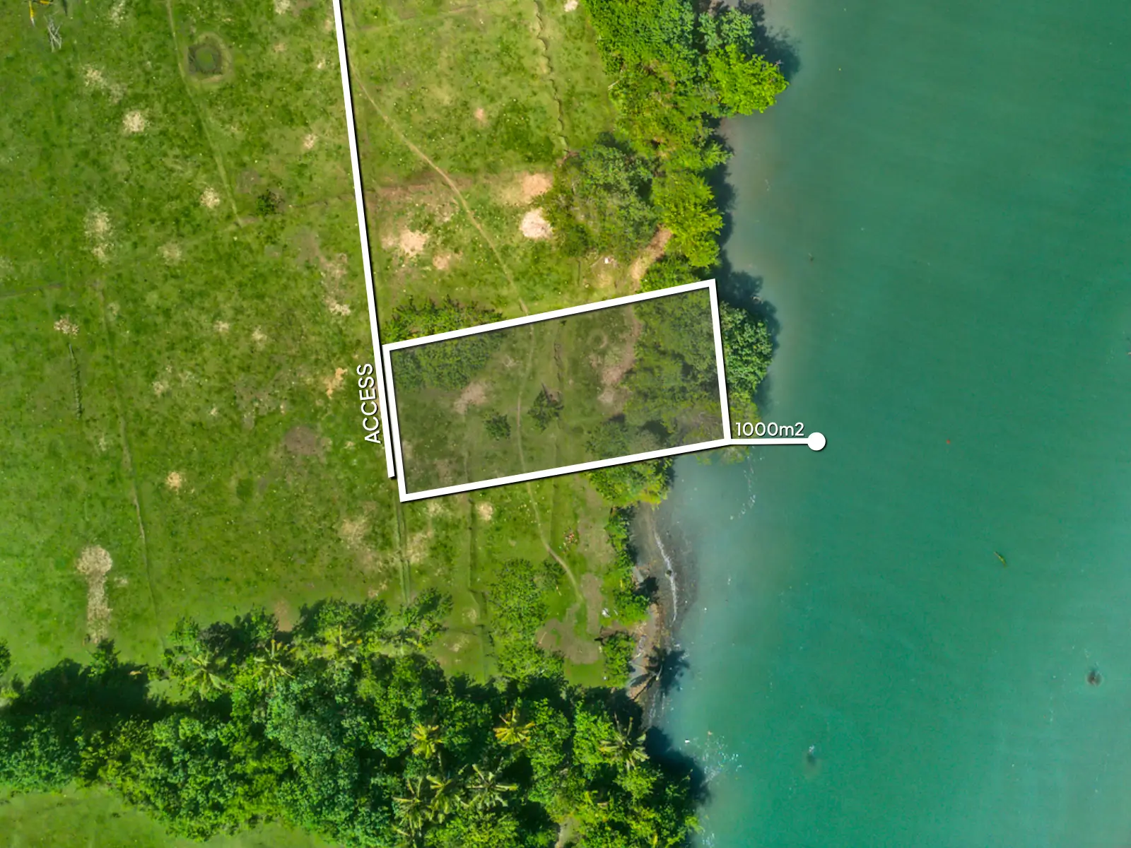 Top-down drone image of a 1,000 m² lagoon-front land plot in West Bali, showing private access, curved river boundary, and open flat land suitable for development.
